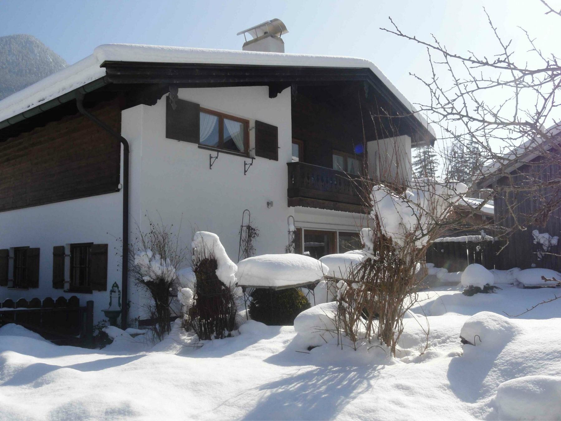 Das Haus im Winter, tief verschneit, vor blauem Himmel